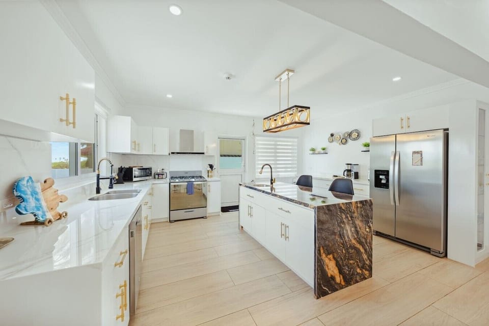 Stylish and functional kitchen featuring a sleek sink, modern refrigerator, elegant gas range oven and stove with an overhead exhaust fan for efficient ventilation.
