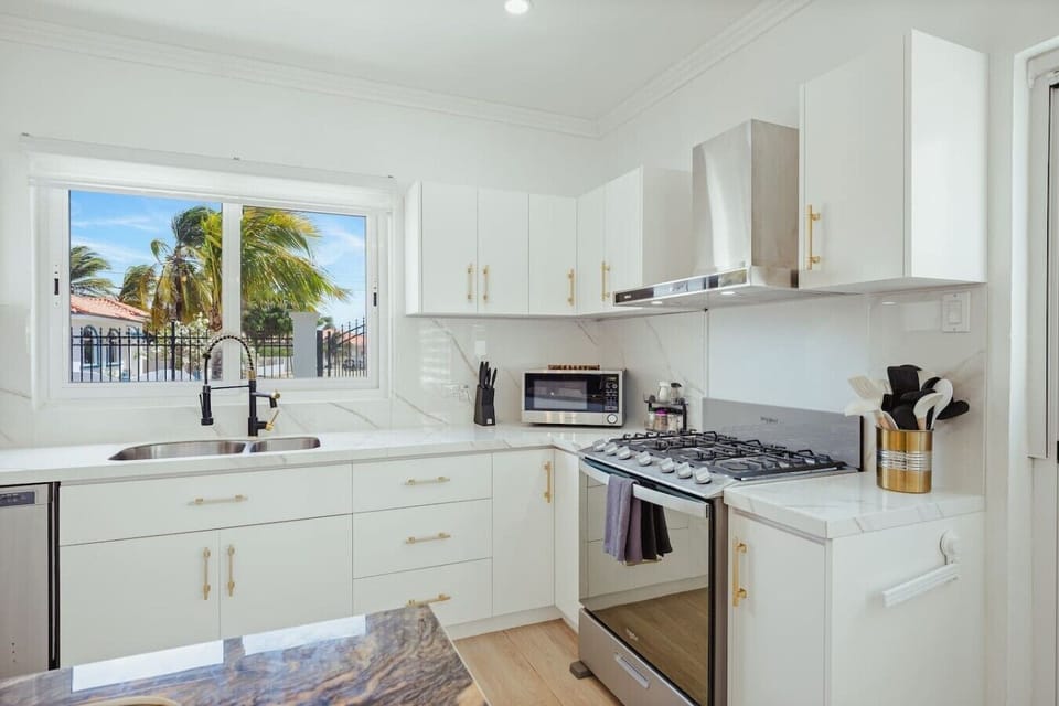 A kitchen view showcasing face to face sinks, ample cabinet storage, and a cool ambient atmosphere for a stylish, wide, and functional cooking space.