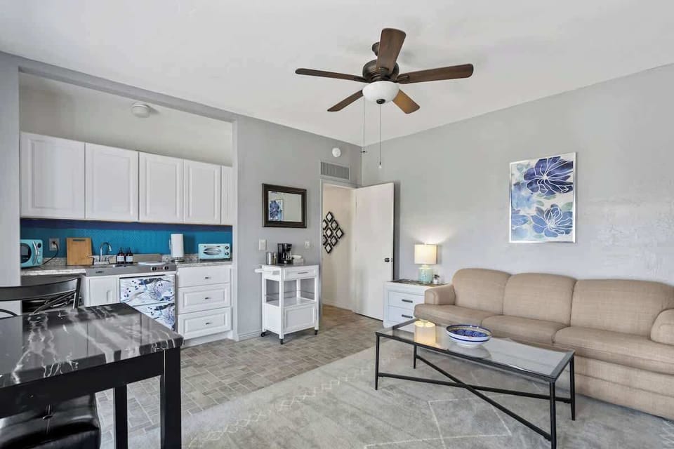 Relax in this light-filled, modern studio featuring a kitchen, comfy seating area, and soothing blue accents, perfect for a cozy and convenient stay.
