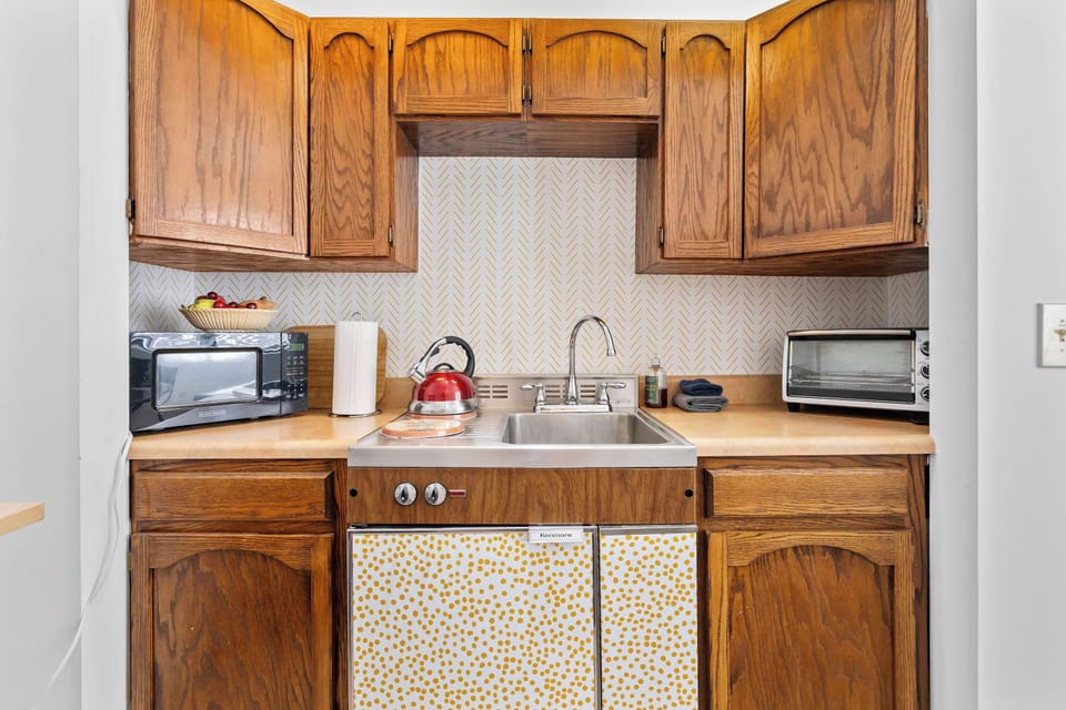 Charming kitchenette with retro flair equipped with a microwave, toaster oven, electric kettle, and all the essentials to whip up simple, satisfying meals.
