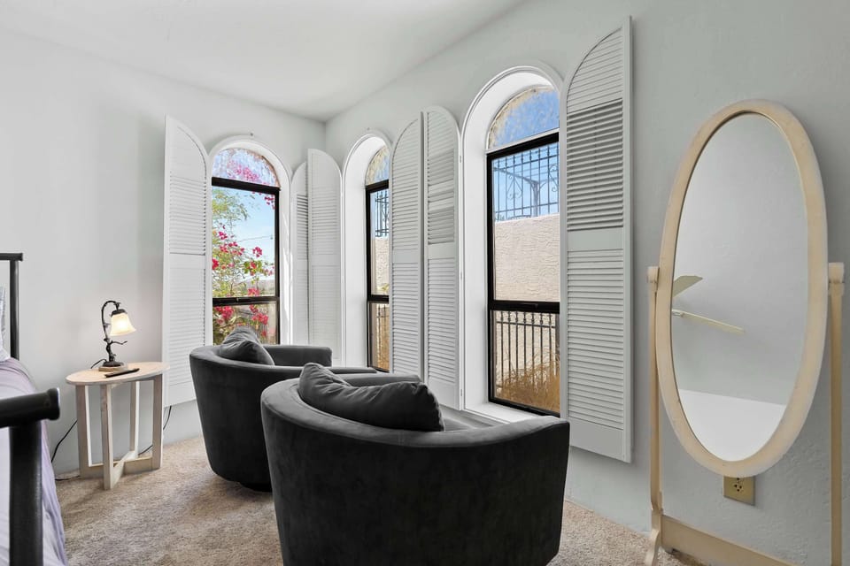 Enjoy peaceful moments in this charming reading nook, framed by elegant arched windows, soft natural light, and cozy velvet chairs.