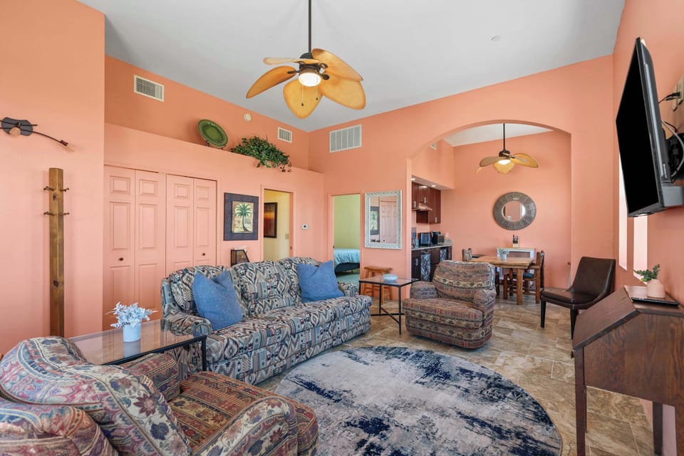 Spacious, Southwest-style living room with vibrant coral walls, cozy seating, and plenty of charm - perfect for gathering, relaxing, or watching a movie.
