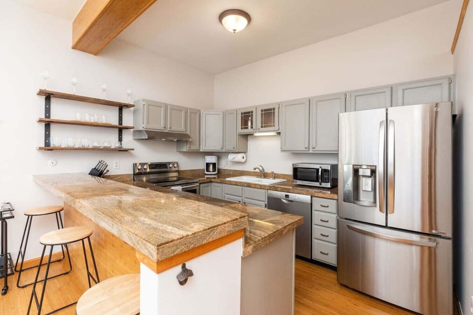 Bright and spacious kitchen with electric range and two-door fridge.