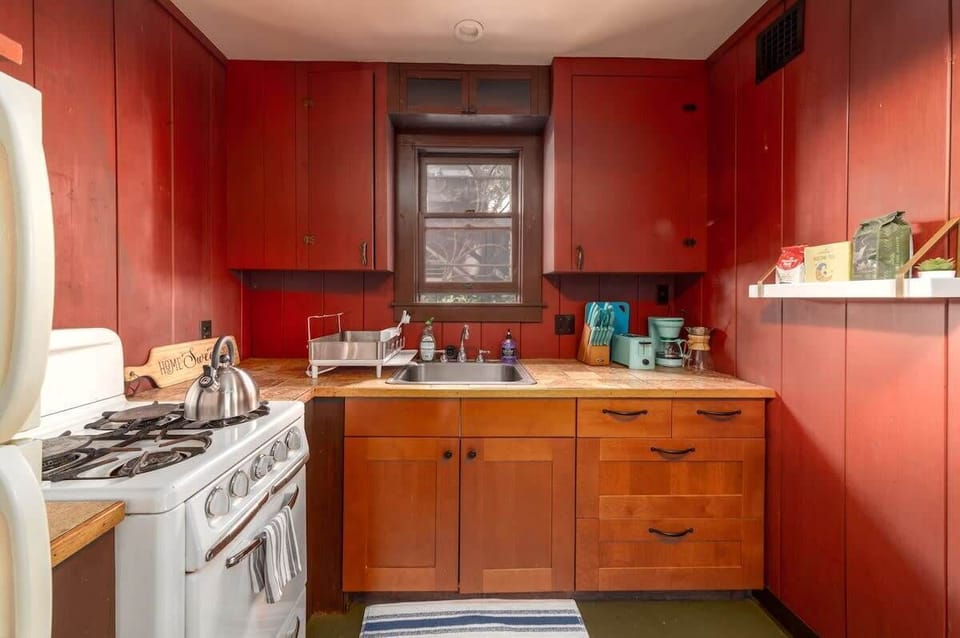 Kitchen with a small footprint but abundant features: gas stove, full fridge, toaster, two coffee maker and a small coffee bar.