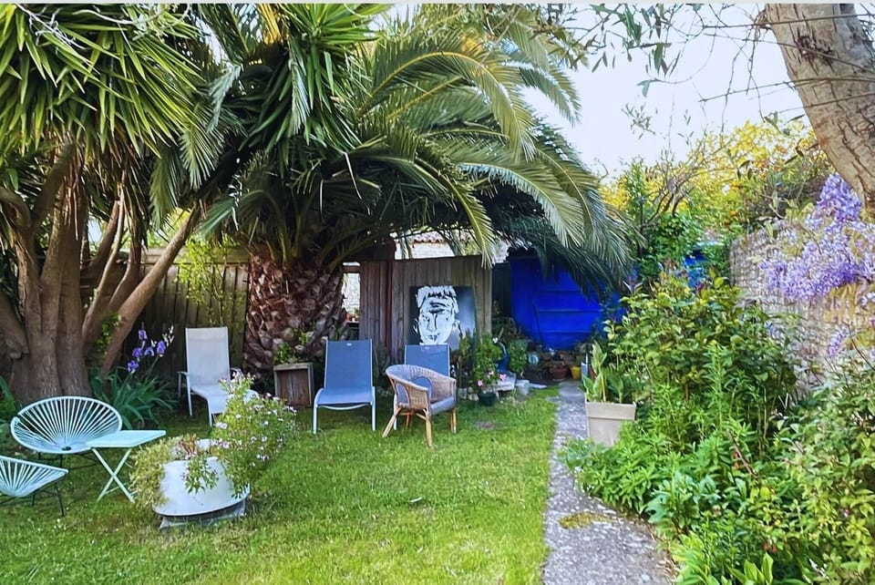 Jardin serein et ombragé : votre pause fraîcheur sous les palmes Entre ombre et lumière, ce coin jardin est un appel au repos. Mobilier confortable, végétation luxuriante et ambiance calme pour un séjour en toute quiétude à La Flotte.