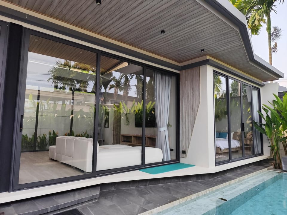 The living room features a comfortable sofa and TV, perfectly positioned to enjoy relaxing views of the private pool.