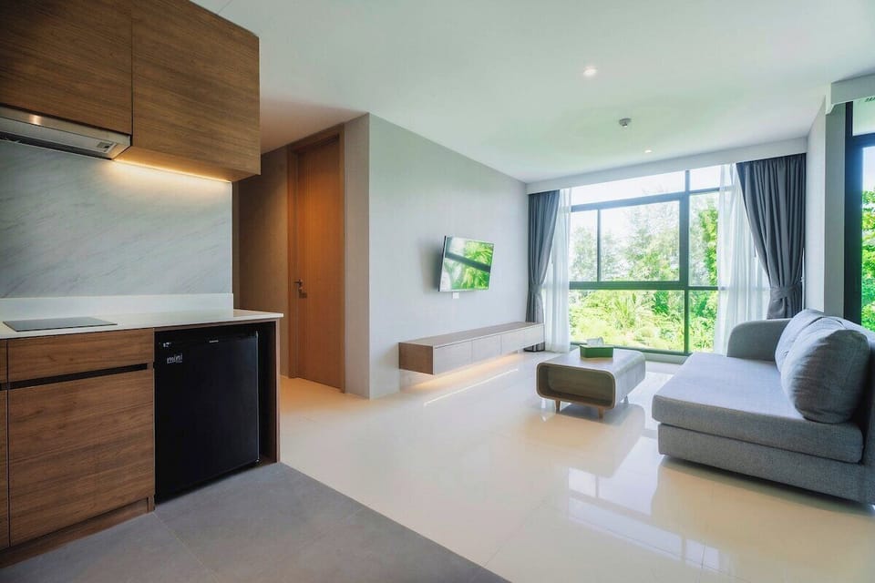 Spacious and bright open-plan living room with a modern kitchen, cozy comfortable sofa, stylish decor, and plenty of natural light.
