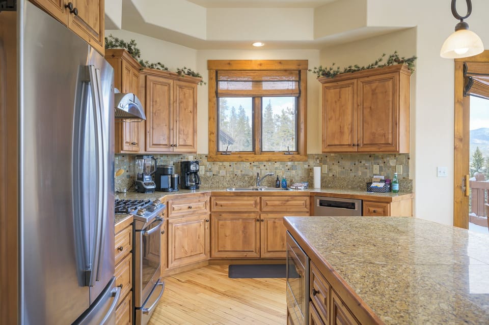 - Corner kitchen layout maximizes space with wide counters and modern design   - Wooden cabinetry stainless steel appliances and tiled backsplash stand out   - Bright window views and full amenities make this kitchen ready for every meal