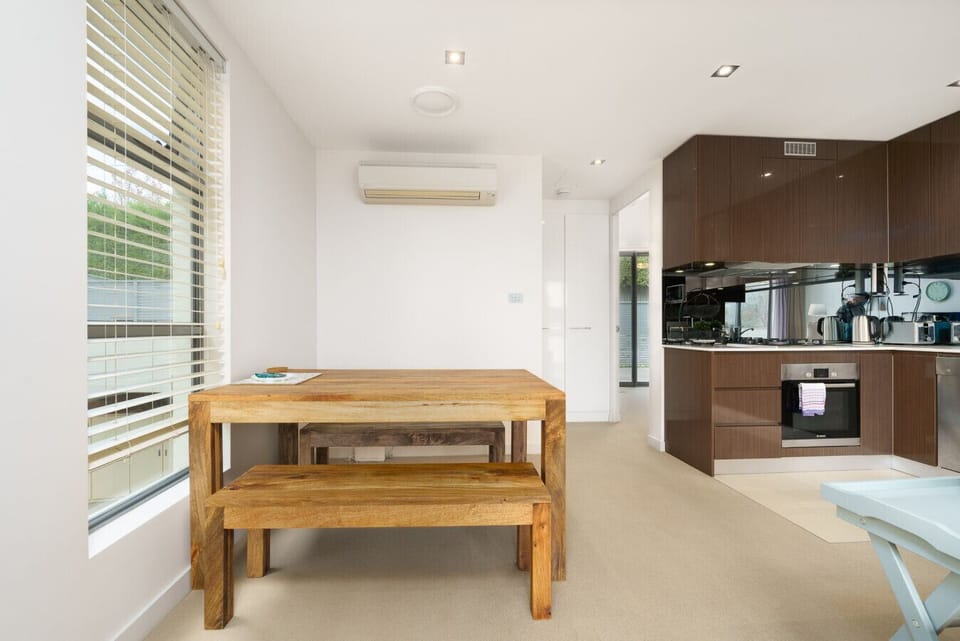 A bright dining space with a sturdy wooden table and bench, perfect for casual meals and gatherings.