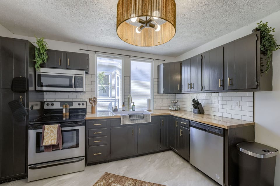Modern kitchen with stainless appliances, wood countertops, and subway tile.