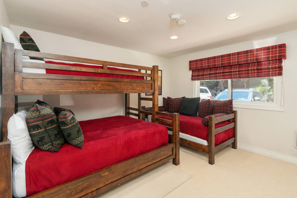 A queen bed with a twin bunk above it along with a twin sized day bed