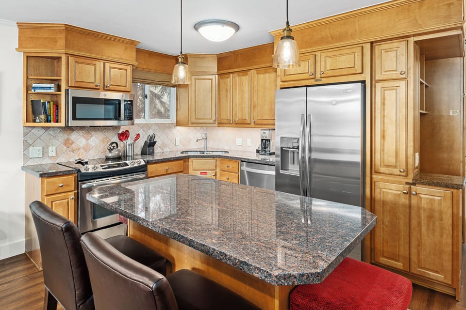 Spacious kitchen with granite countertops and large center island with bar seating for 4. Fully stocked with stainless steel appliances and everything guests need for comfortable meal preparation.