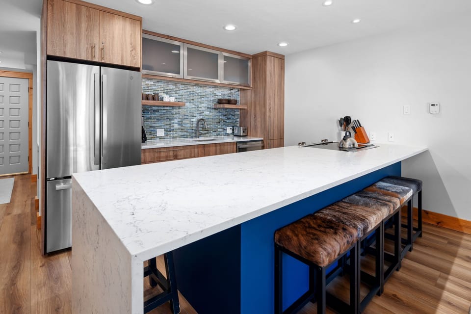Spacious kitchen with stone countertops and large island with bar seating for 4. Fully stocked with stainless steel appliances and everything guests need for comfortable meal preparation.