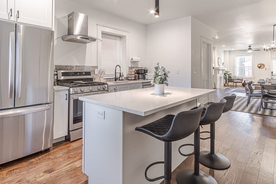 Modern and fully equipped kitchen featuring a spacious island with 3 bar stools—perfect for casual meals or morning coffee. Includes sleek stainless steel appliances like a refrigerator, oven, and more for all your cooking needs.