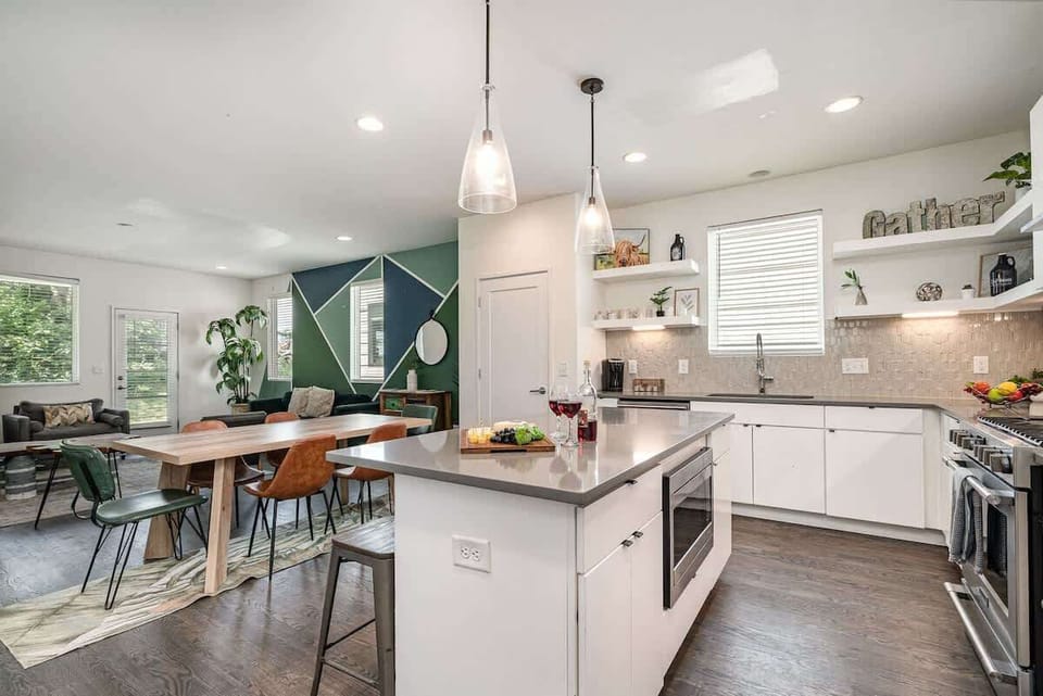Bright open-concept kitchen featuring a quartz-topped island with bar seating, stainless steel appliances, and abundant natural light streaming through the windows. (1st Floor)