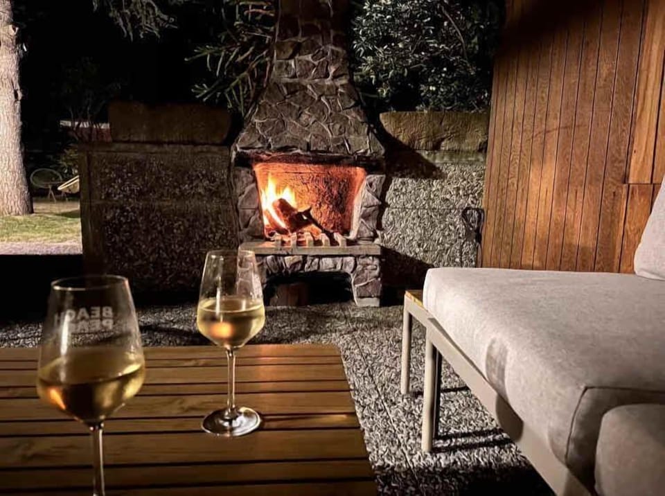 Überdachte Terrasse im Garten mit Loungesofa, Stühlen, Tisch und einem Grill/ Außenkamin für entspannte Abende. 