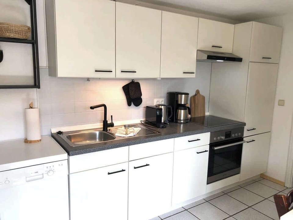 Offene Küche mit Nespressomaschine, Kaffeemaschine, Wasserkocher, Geschirrspüler und Gefrierfach.