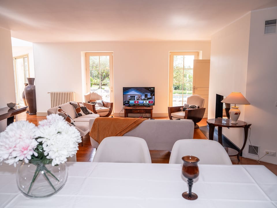 Lounge/dining room: 2 sofas + armchairs - Coffee table - TV with orange subscription - Wood-burning stove - Table for 10 - Light-filled space with large windows.