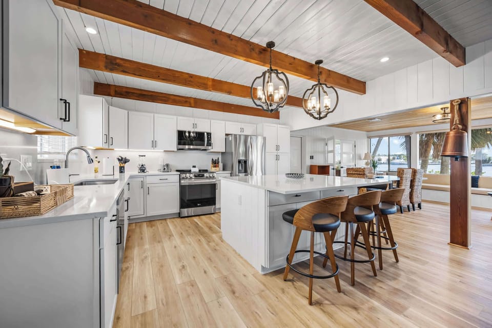 Modern kitchen with white cabinetry, wood beams, and a large island with seating.