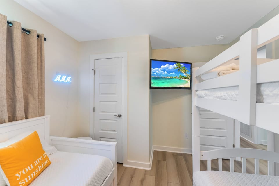 Your cheerful bedroom features a comfy bed and bunk beds, perfect for families. Watch your favorite shows on the wall-mounted TV after sunny beach adventures.