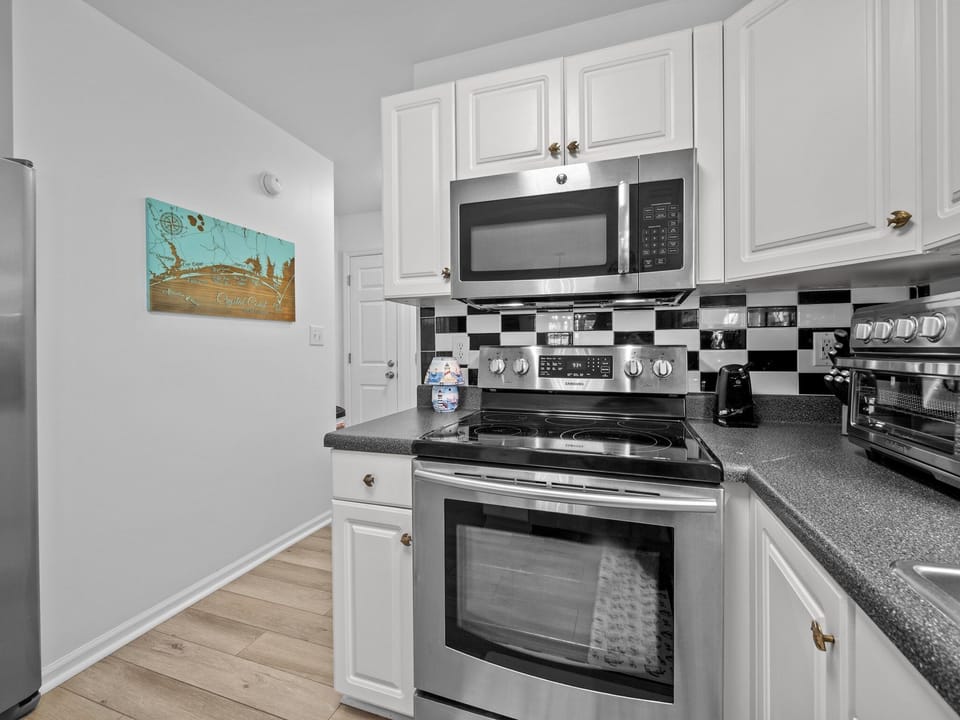 Your fully equipped kitchen features stainless steel appliances, white cabinetry, and granite countertops perfect for preparing meals during your stay.
