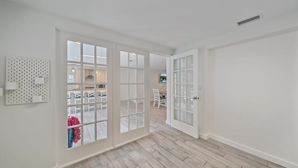 French doors open up the home, providing a bright and airy flow between the main living area, dining room, and the fully updated kitchen, perfect for seamless coastal entertaining.
