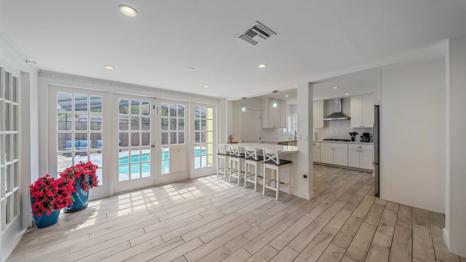 Enjoy the bright, open-concept living space, featuring a breakfast bar and French doors that flood the room with natural light and lead directly to the private pool.
