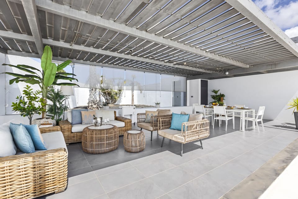 Outdoor seating area under pergola with comfortable sofas.