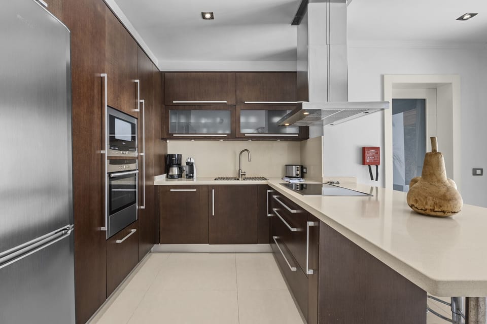 Spacious kitchen with dark wood cabinets and white countertop.