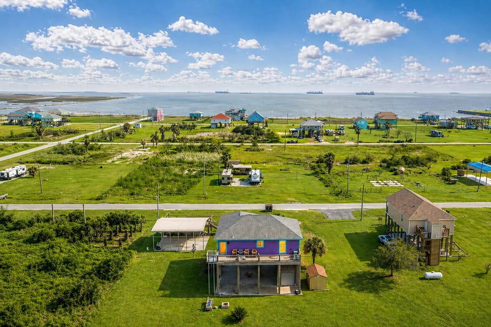 Aerial neighborhood and coastline view highlighting proximity to beach and surrounding homes.