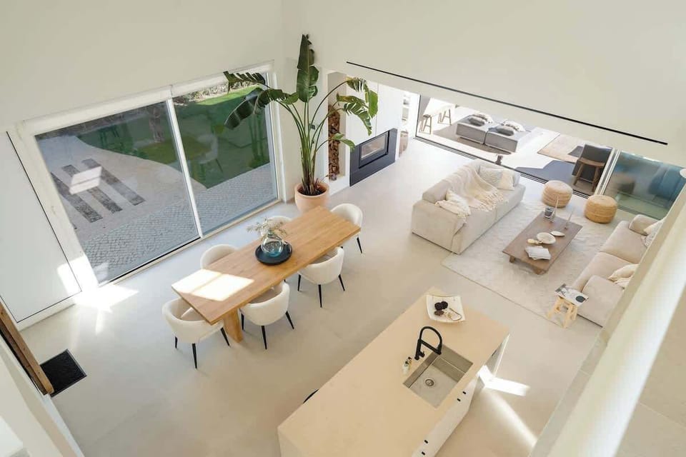 A stunning open-concept space with a soaring double-height ceiling, blending the kitchen and dining area seamlessly. Natural light floods the room, creating an airy, inviting atmosphere—perfect for gatherings, dining, or simply unwinding in style