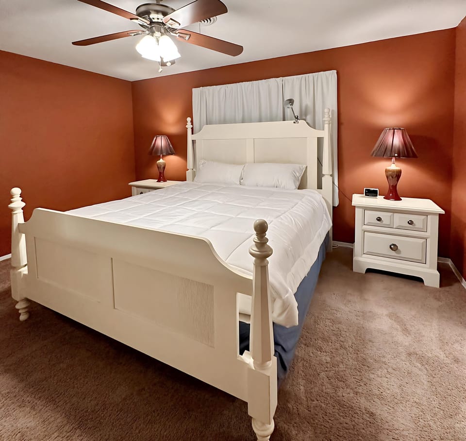 Spacious and cozy bedroom featuring a plush king-size bed with crisp white linens, warm accent lighting, and matching nightstands.