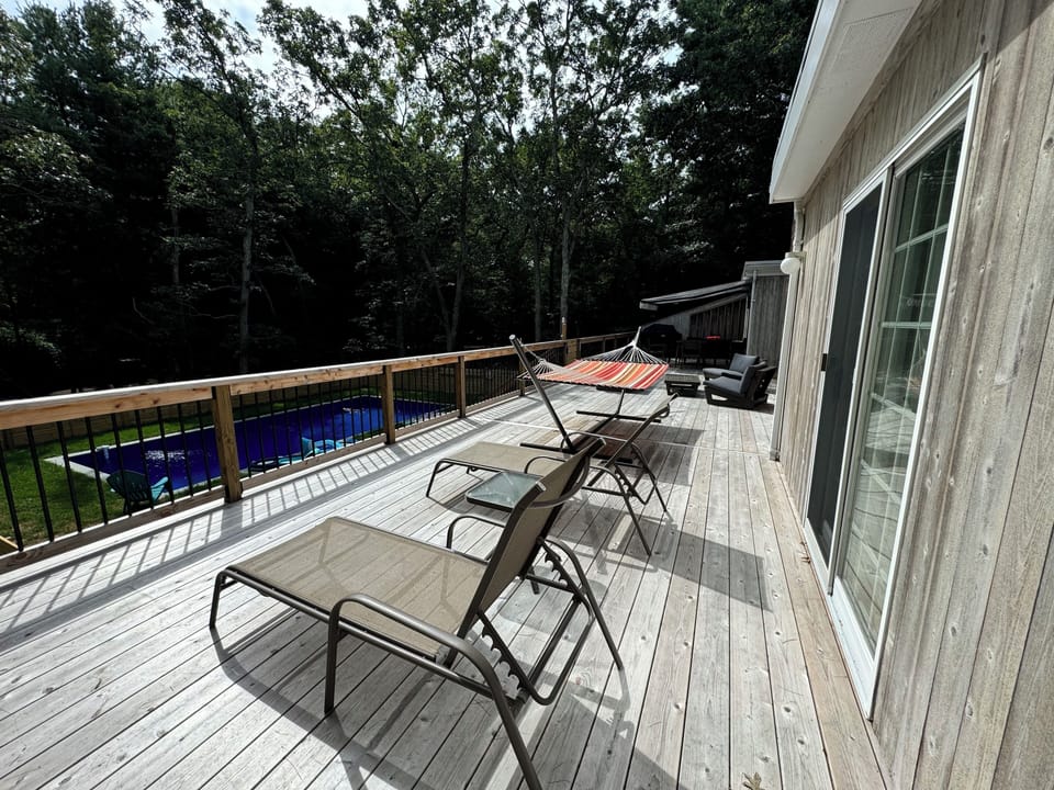 Large deck overlooking pool with plenty of seating including hammock