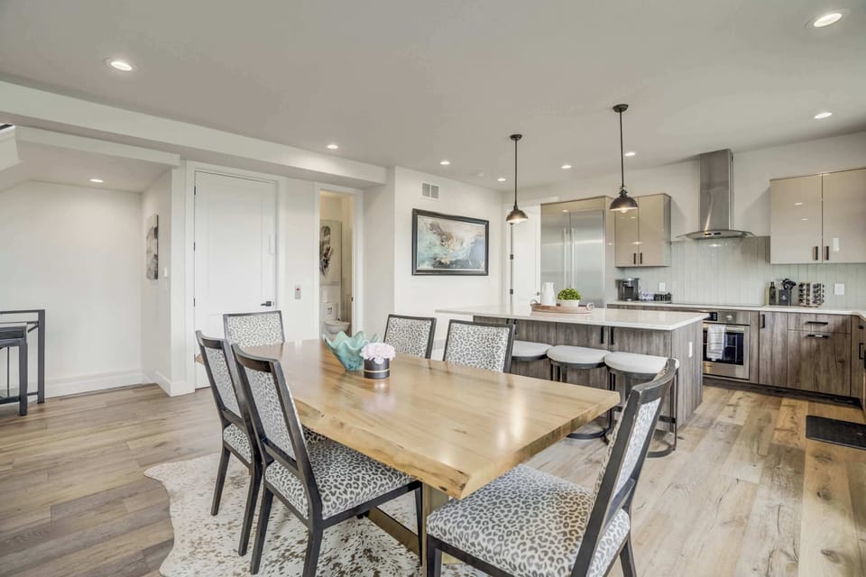 Elegant dining area with a spacious wooden table, modern lighting, and open access to the kitchen—perfect for shared meals and entertaining.

