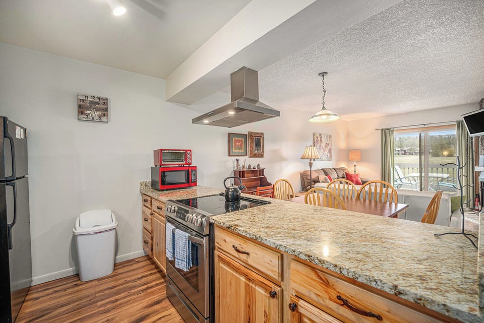 - Open concept kitchen features full size appliances and granite island cooktop
- Enjoy meals, cook together, or relax nearby in the connected living area
- Red microwave and rustic wood finishes add charm and personality throughout