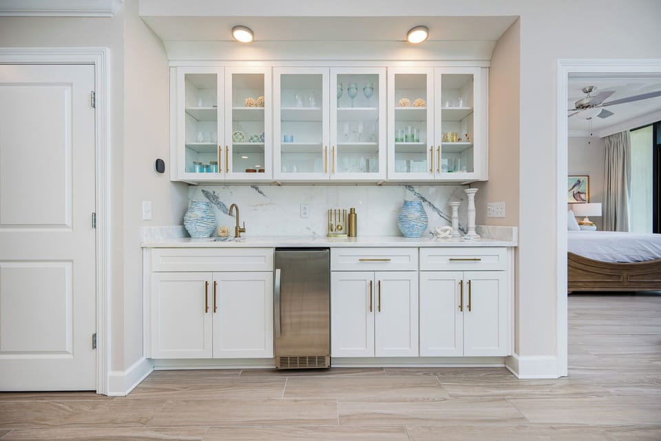 Enjoy refreshments from this decorative wet bar, featuring an elegant glassware display and coastal accents