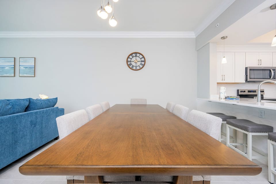 Gather around the long wooden dining table, with a beachfront view from the balcony