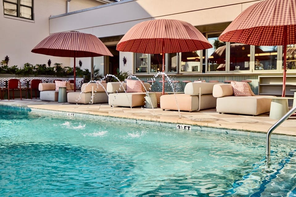 Drift into leisure under blush-toned shade as soft splashes echo the rhythm of a relaxed Charleston day.