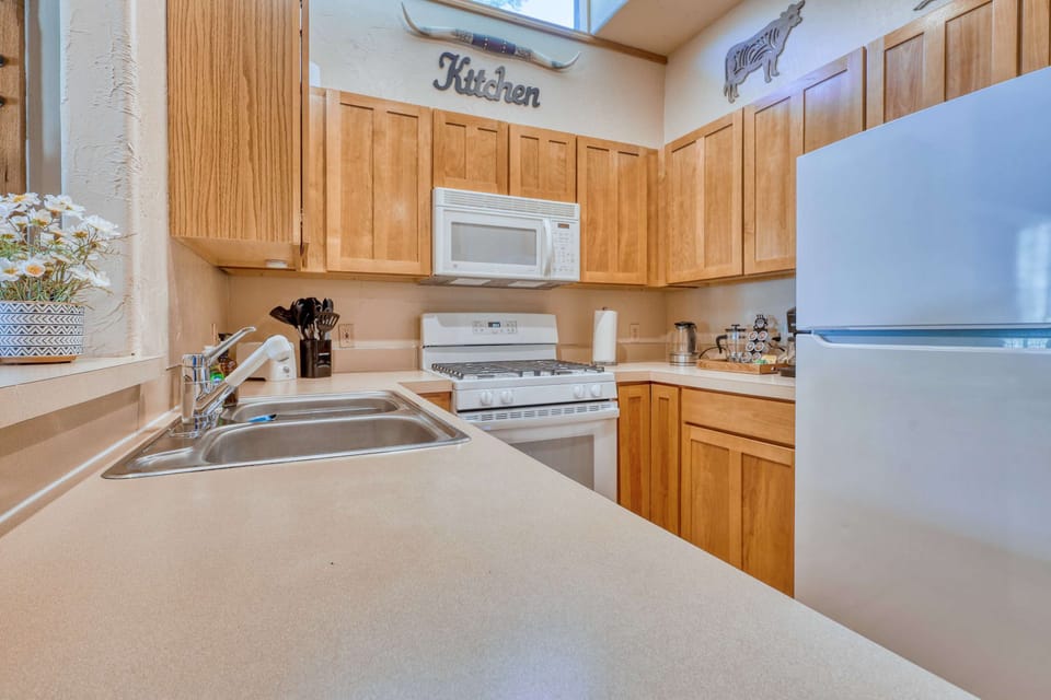 The kitchen features a modern gas stove and oven, a large refrigerator, a microwave, and a dishwasher, all surrounded by rustic wood cabinetry that adds to the cabin's warm, inviting feel. CB1