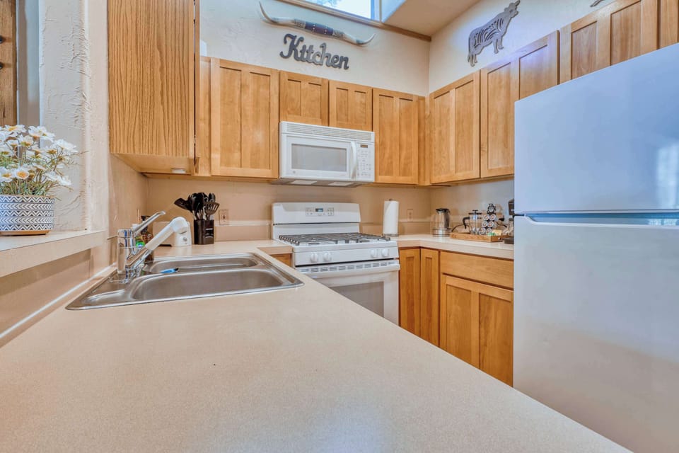The kitchen features a modern gas stove and oven, a large refrigerator, a microwave, and a dishwasher, all surrounded by rustic wood cabinetry that adds to the cabin's warm, inviting feel.