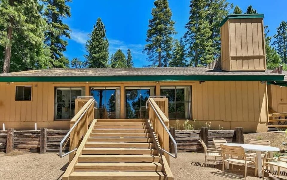 A rustic yet refined building framed by towering pines, with a large outdoor deck for gatherings. 🌲