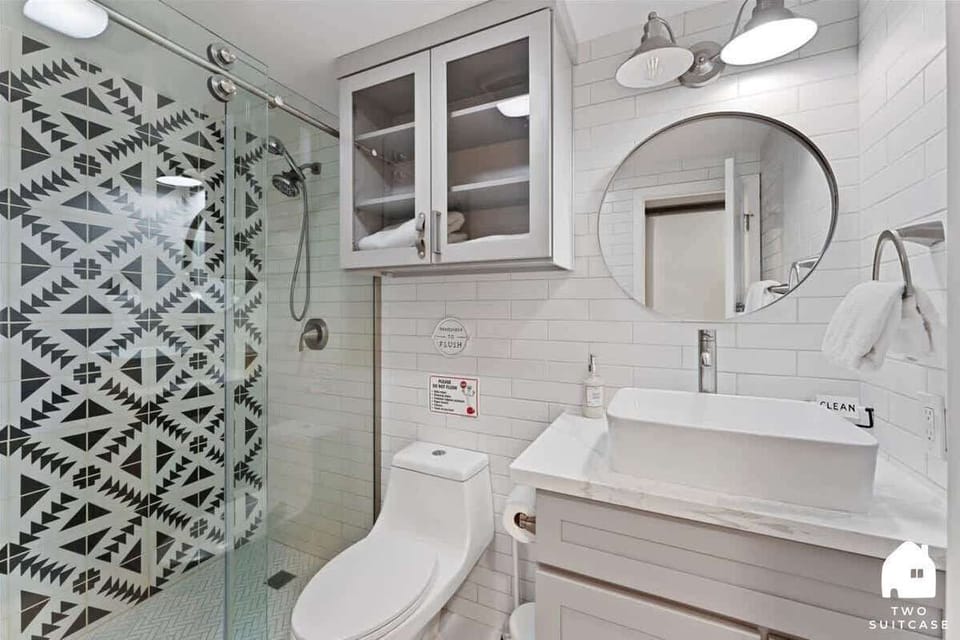 A bright, polished bathroom with a patterned shower curtain and fresh white finishes. 🚿