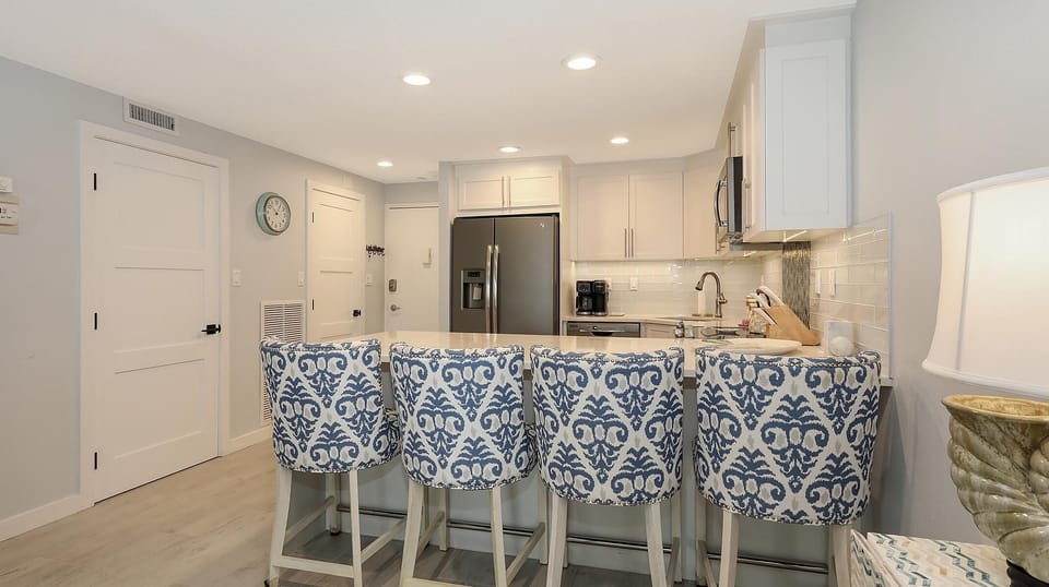 White cabinetry and subway tile backsplash highlight the kitchen, with a stainless steel refrigerator and built-in microwave.
