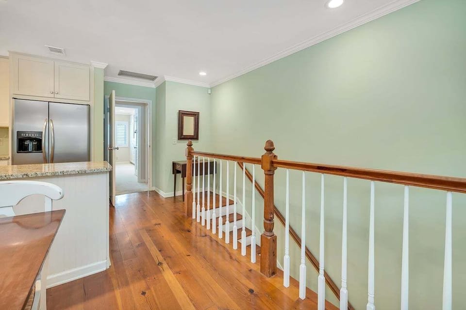 Upper hallway with hardwood floors and staircase railing