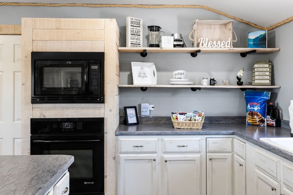 Thoughtfully stocked kitchen corner with charming farmhouse shelves, modern appliances, and complimentary breakfast goodies.