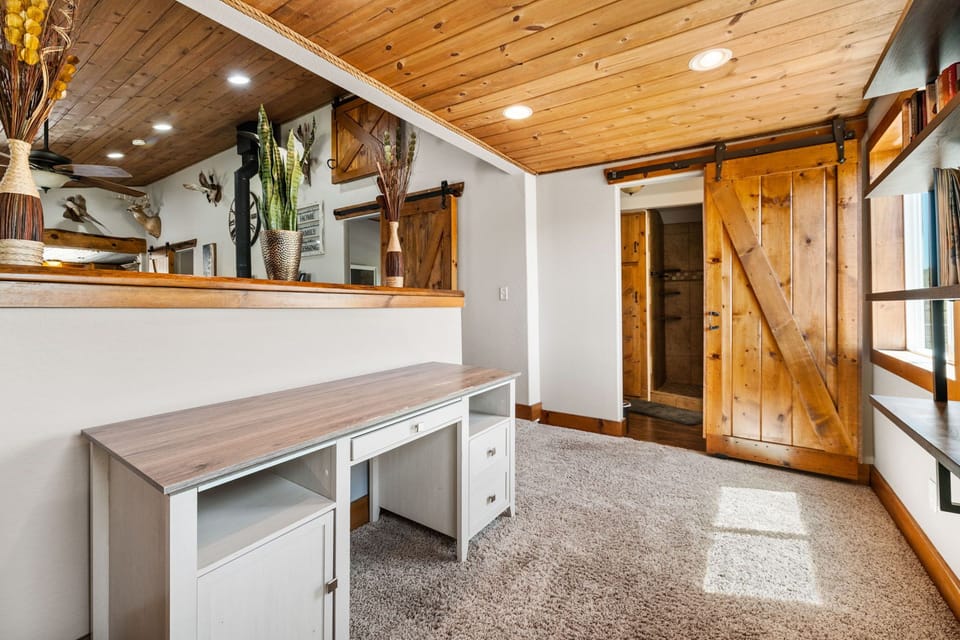 This cozy nook doubles as a dedicated work or play area, complete with a desk, bookshelves, and charming barn-style touches.