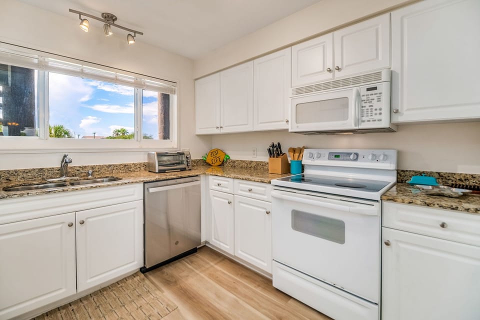 Updated white kitchen with granite counters and breakfast bar - fully equipped for vacation cooking