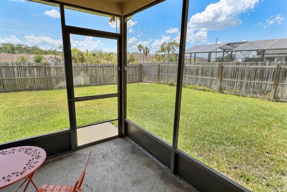 Enjoy a private screened patio overlooking a spacious fenced backyard, offering a peaceful outdoor setting to relax, enjoy the fresh air, or spend quality time with family during your stay.