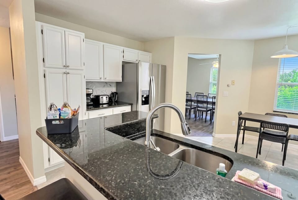 Bright and functional, this kitchen features sleek granite countertops that complement the crisp white cabinetry. Enjoy the spacious layout that invites meal preparation and gatherings, making it a delightful hub for your stay.