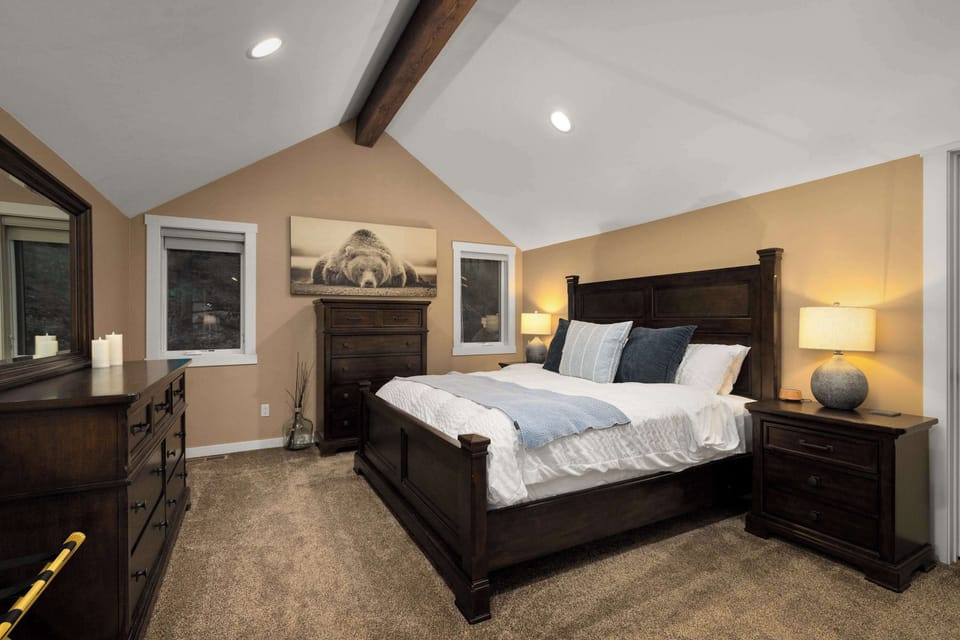 Wake up in comfort and style in this spacious master bedroom with luxury bedding, natural light, and peaceful Montana surroundings.